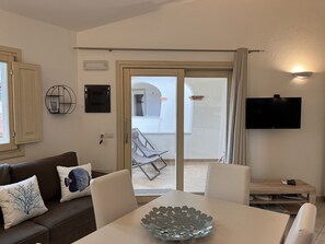 A modern living room with a sofa, a coffee table, and a TV mounted on the wall.