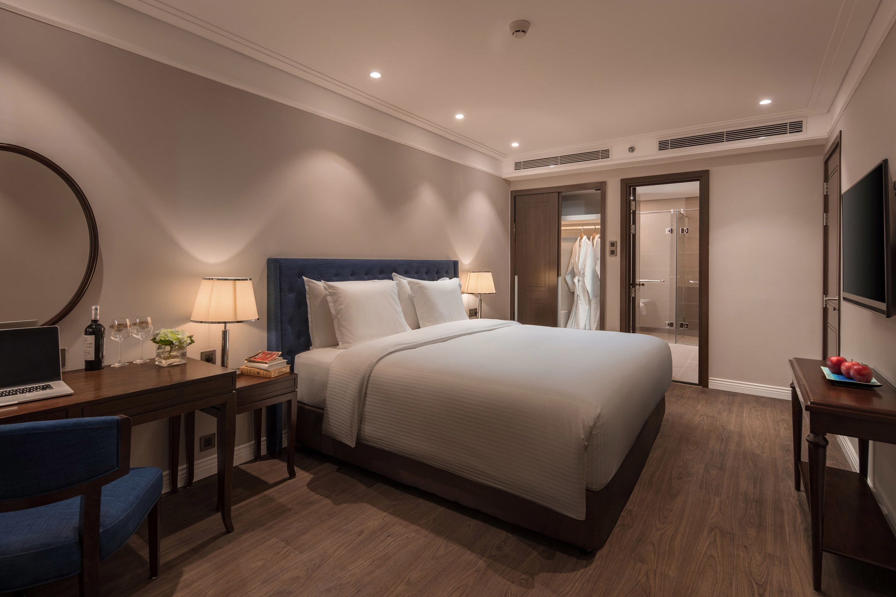 A hotel room with a bed, desk, chair, and a TV.