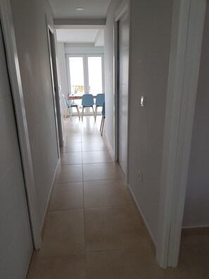 A hallway with a dining area at the end, featuring a table and chairs.