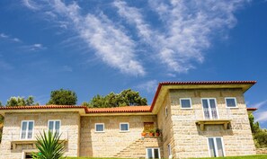 Un bâtiment en pierre avec un toit recouvert de tuiles rouges, de nombreuses fenêtres et un balcon.