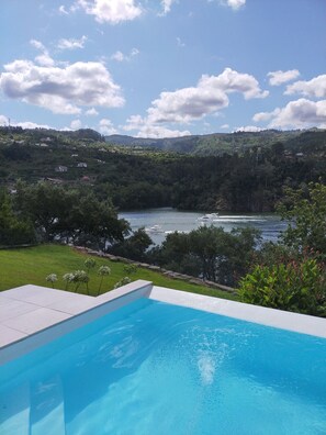A swimming pool with a view of a lake and hills in the background.