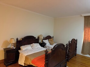 Une chambre à coucher avec un lit double, deux tables de chevet, une lampe et une fenêtre avec des rideaux.