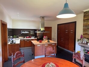 Une cuisine moderne avec des meubles en bois, un îlot central et un coin repas doté d’une table ronde.