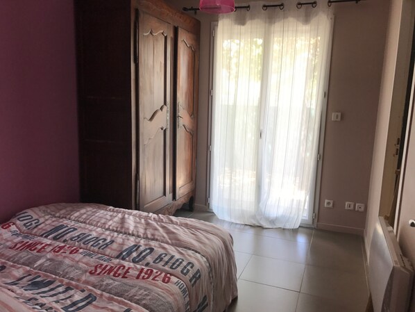 Une chambre à coucher avec un lit, une armoire et une fenêtre ornée de rideaux légers.