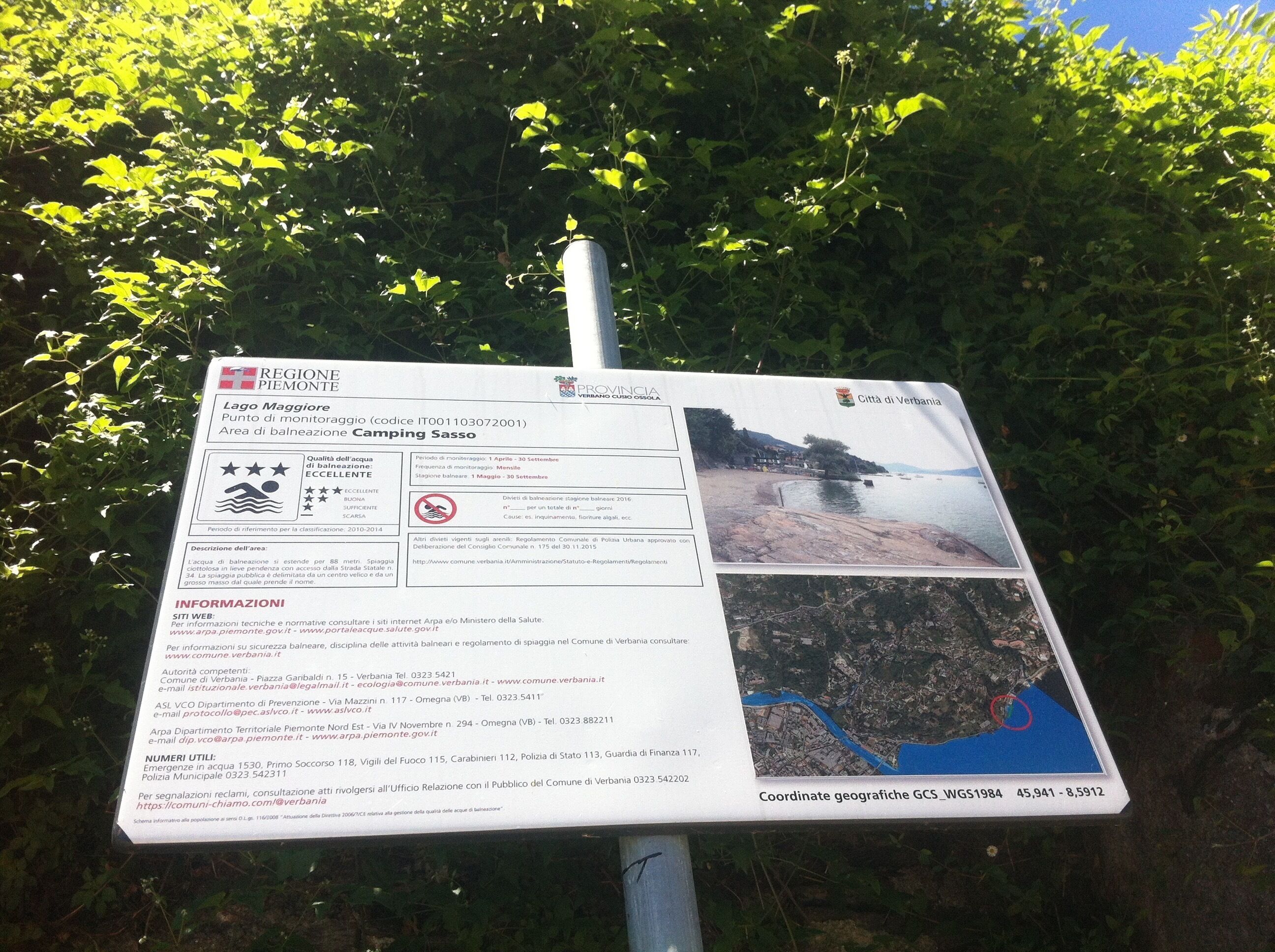 Un panneau indiquant une zone de surveillance de la qualité de l’eau, avec une carte et les numéros de téléphone à contacter en cas d’urgence.