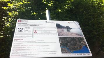 Un panneau indiquant une zone de surveillance de la qualité de l’eau, avec une carte et les numéros de téléphone à contacter en cas d’urgence.
