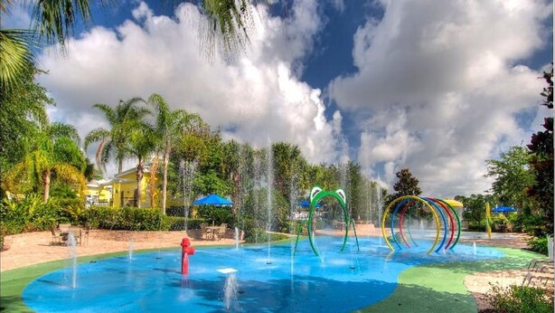 A swimming pool with water features, surrounded by palm trees and a clear sky.