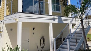 A two-story house with a balcony, a front door, and a staircase leading to the upper level. - Kozy Kottage on private road. 2 minute walk to private beach.  Pet friendly! (Englewood)