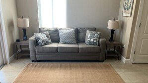 A living room with a grey sofa, patterned cushions, two side tables with lamps, and a herringbone-patterned rug. - Kozy Kottage on private road. 2 minute walk to private beach.  Pet friendly! (Englewood)