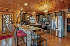 A wooden cabin interior with a kitchen, stone bar, and seating area. - Unmatched EPIC Smoky Views! Luxe Amenities, Best Location & Service! Pristine! (Gatlinburg)