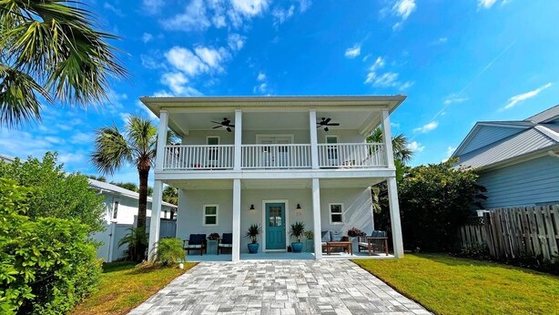 A two-story house with a front porch, a covered patio, and a paved driveway. - Beautiful, well-appointed three-bedroom beach house 300 yards from the beach. (St Augustine)