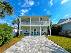 A two-story house with a front porch, a covered patio, and a paved driveway. - Beautiful, well-appointed three-bedroom beach house 300 yards from the beach. (St Augustine)