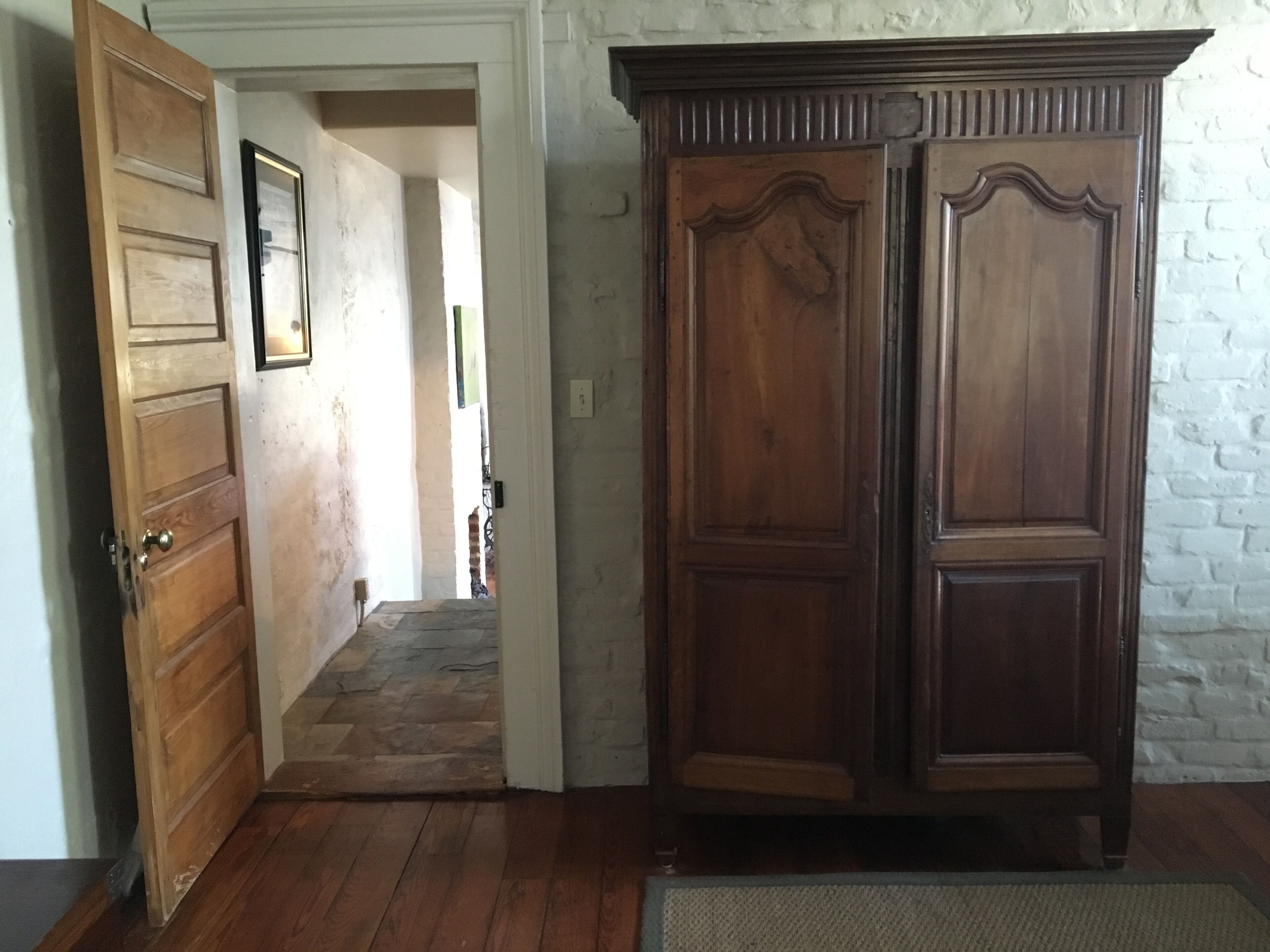 A hallway with wooden doors and a large wooden cabinet.