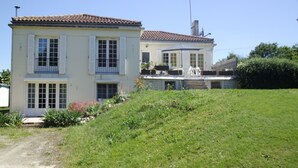 Una casa de dos pisos con techo de tejas, un porche delantero y un pequeño jardín.