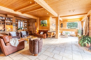 A spacious living area with wooden beams, leather sofas, and a fireplace.