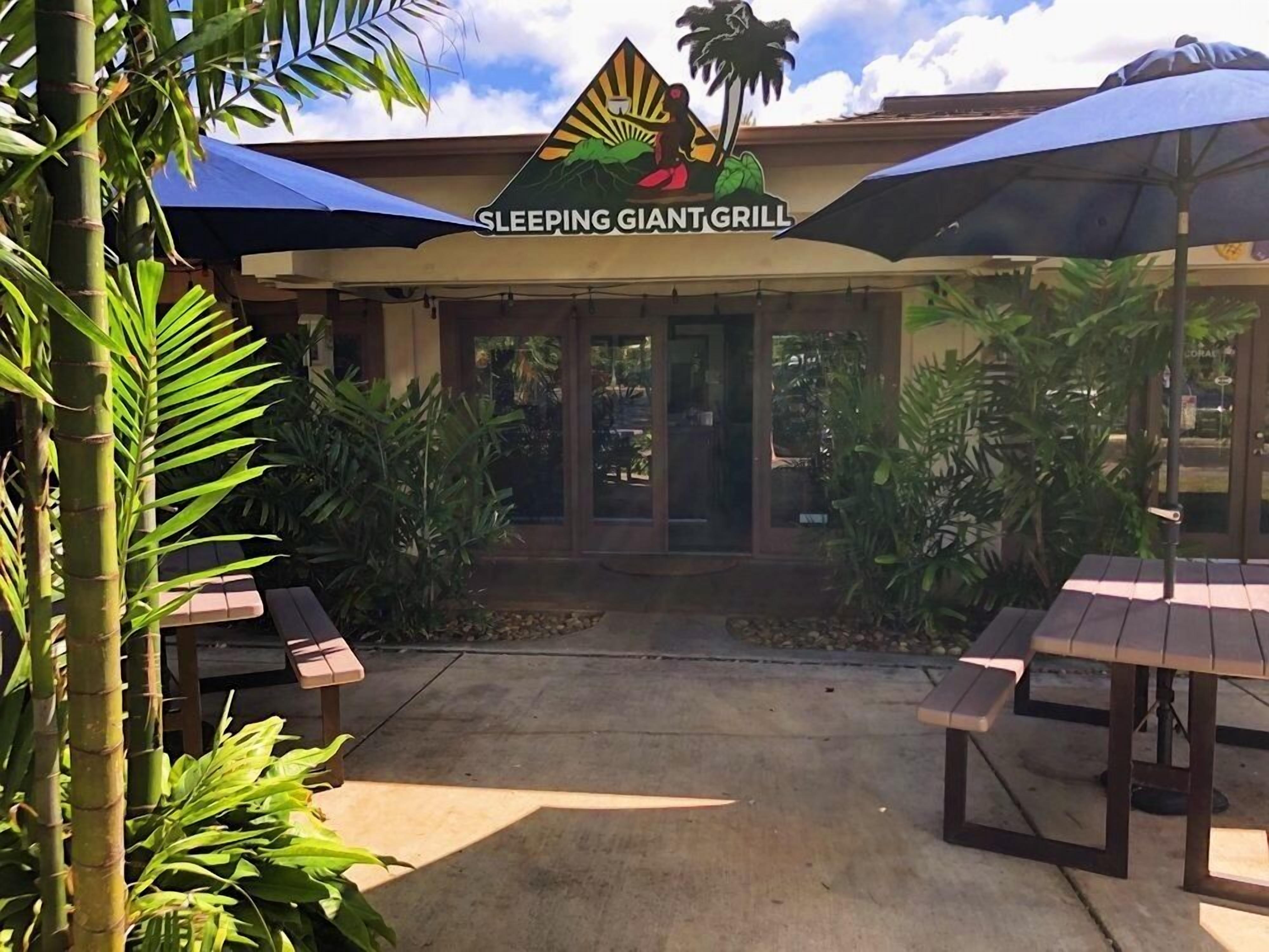 An outdoor seating area with tables and umbrellas at the Sleeping Giant Grill.
