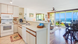 Una cocina moderna con una isla grande, un comedor con vistas y una amplia sala de estar con balcón sobre el océano.