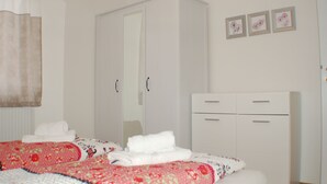 Un dormitorio con una cama, dos armarios blancos y tres cuadros en la pared.