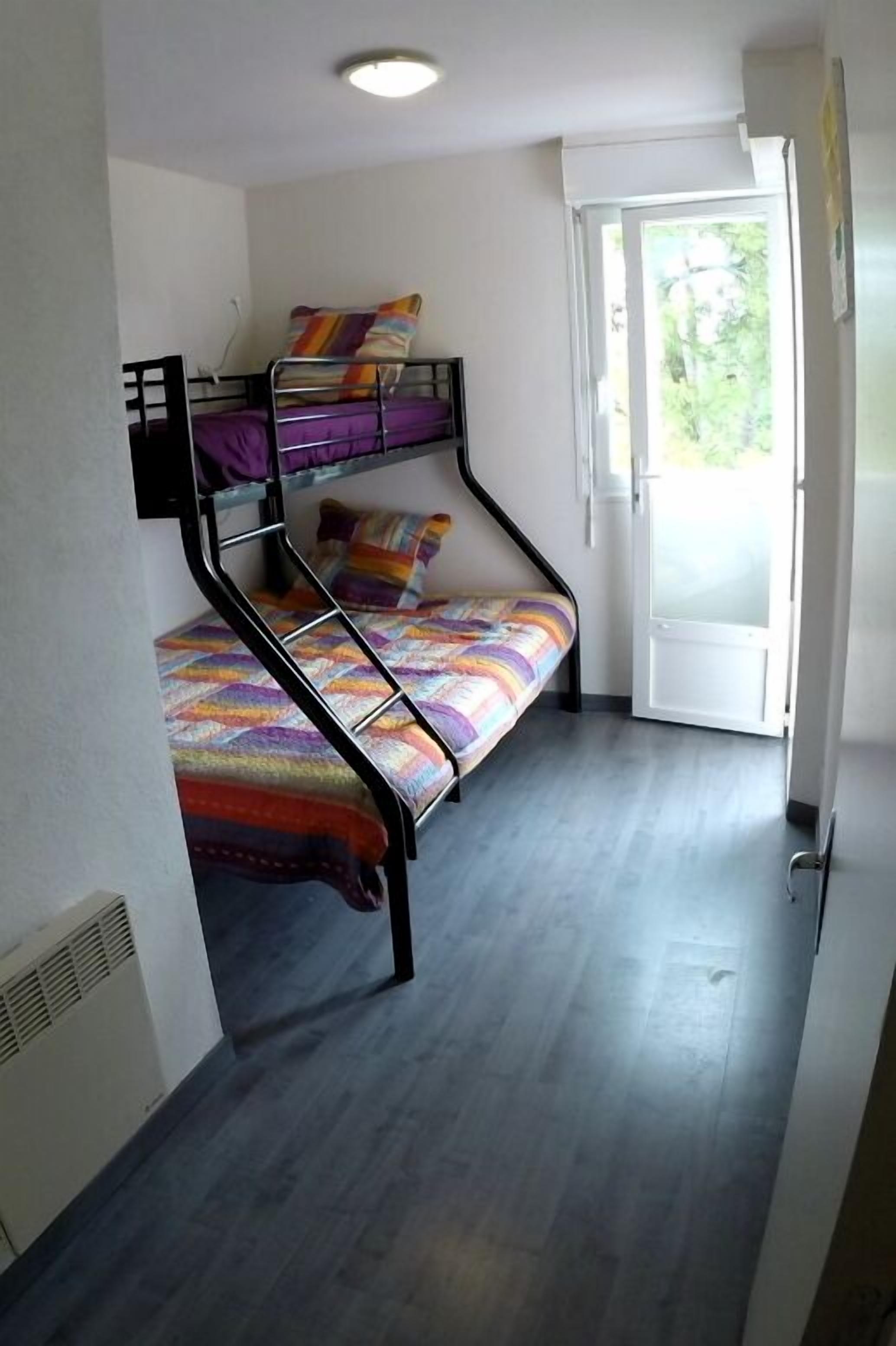 A bunk bed room with a view of greenery outside.
