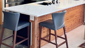 A modern kitchen with dark wood cabinets, stainless steel appliances, and a large island with bar stools.