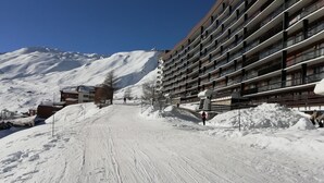 Pista de esquí nevada con un edificio moderno y varios balcones.