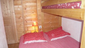 Una cama litera de madera con colcha y almohadas a cuadros rojo y blanco.