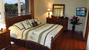 A bedroom with a wooden bed, a ceiling fan, a dresser, a mirror, a television, and a potted plant. -  Now with AC!    Ocean View  2 bd 2 Bath, 1 story condo at the Makahuena. (Poipu Beach)