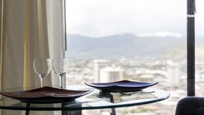 Ein Tisch mit zwei Weingläsern und zwei Tellern, vor einem Fenster mit Blick auf die Stadt.