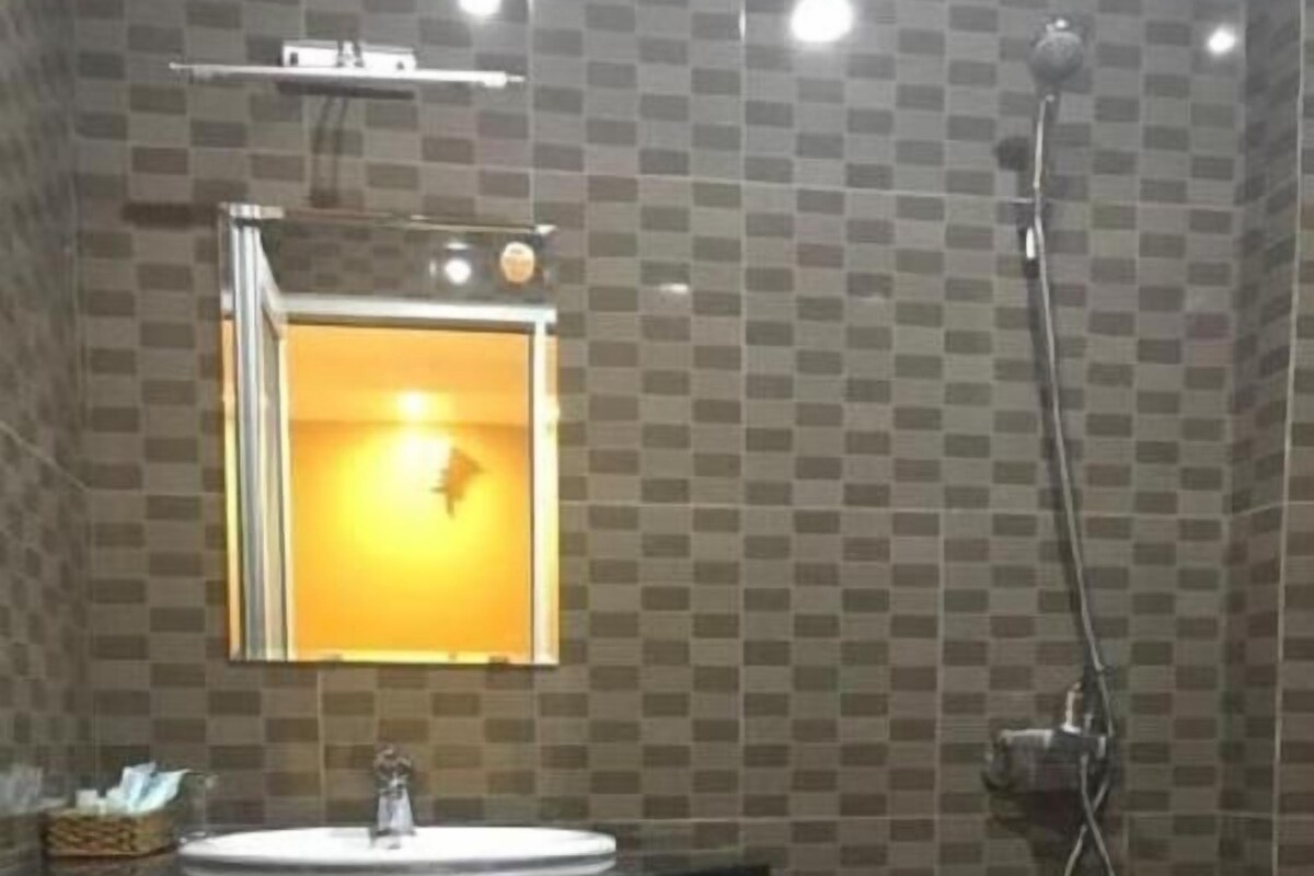 Un baño con pared de azulejos, lavamanos con espejo y ducha.