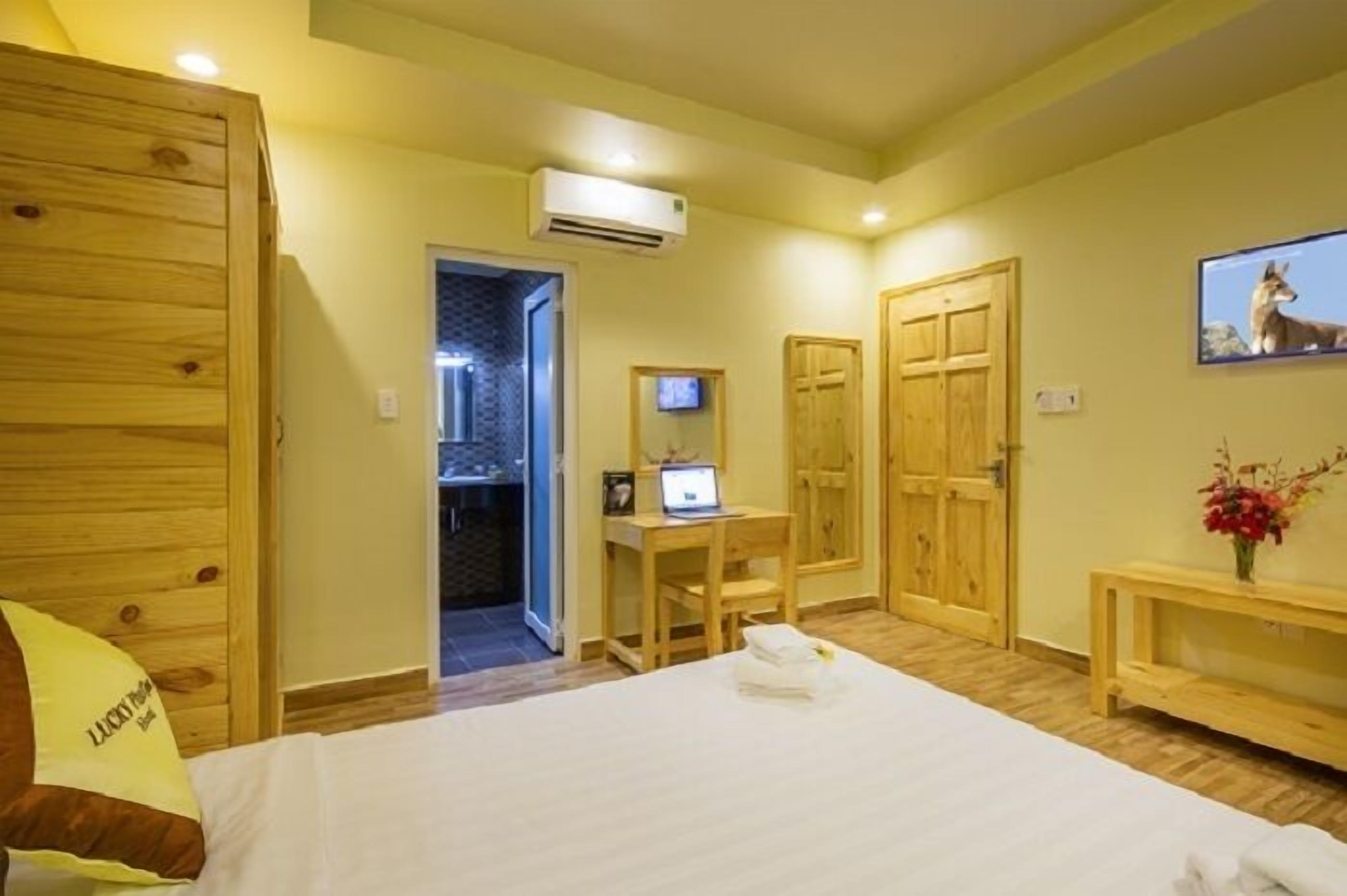 A hotel room with a bed, wooden wardrobe, desk, and a TV.