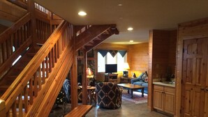 A wooden staircase leading to a living area with a fireplace, a television, and a sofa. - Explore Colorado! VeryPrivate. Peaceful, AlpineLuxury on 3 Acres. 2 MilesToTown (Breckenridge)