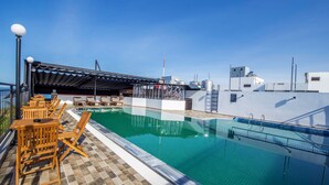 An outdoor swimming pool with lounge chairs and a covered seating area. - Levan Hotel (Phu Quoc)