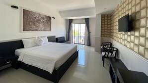 A modern hotel room with a large bed, a flat-screen TV mounted on a textured wall, and a view of the outdoors through a sliding door. - Levan Hotel (Phu Quoc)