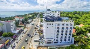 A multi-story hotel with a prominent 'Sea View' sign, a busy street with vehicles, and a coastal backdrop. - Levan Hotel (Phu Quoc)