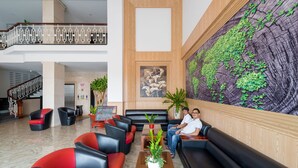 A lobby with a staircase, black and red seating, a large wall mural, and a reception desk. - Levan Hotel (Phu Quoc)