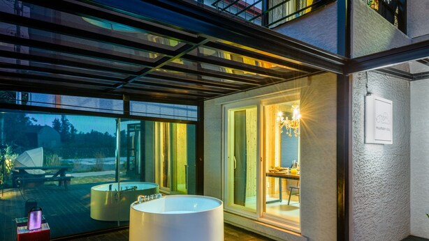 Casa de banho moderna com uma banheira grande, zona de duche com proteção de vidro e vista para o exterior.