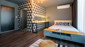 Quarto moderno com parede xadrez, mesa de cabeceira com espelho, cama com várias almofadas e um aparelho de ar condicionado.
