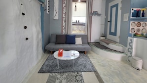 A compact living space with a grey sofa, a small round table, and a patterned rug. - JejuMermuri (Seogwipo)