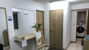 A reception area with a reception desk, a plant, a sign indicating no smoking, and a door labeled with a number. - Odori Backpackers (Sapporo)