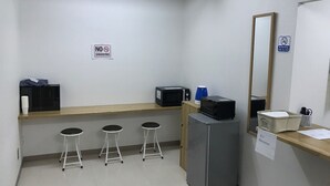 A small, clean room with a microwave, refrigerator, and three stools. There are signs indicating no smoking and a reception area. - Odori Backpackers (Sapporo)