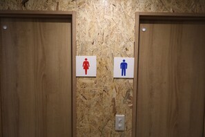 Two wooden doors with a wall-mounted sign indicating a men's and a women's restroom. - Odori Backpackers (Sapporo)