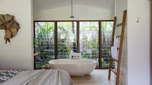 A bathroom with a freestanding bathtub, a wooden ladder, and a large window with a view of greenery. - The Boathouses at Leaves & Fishes (Lovedale)