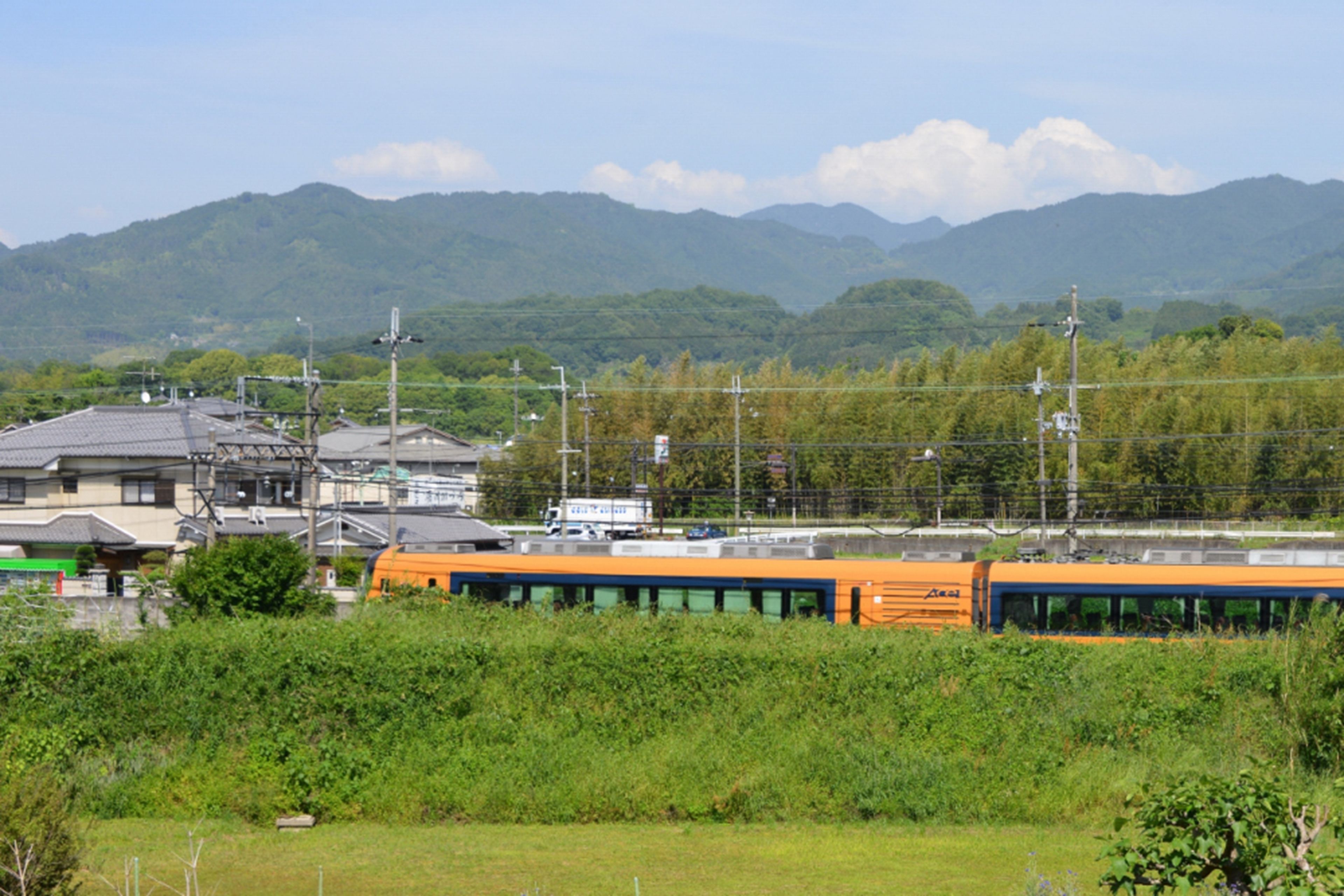 A train station with a train, buildings, and mountains in the background.