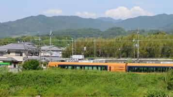 A train station with a train, buildings, and mountains in the background.