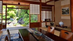A traditional Japanese room with tatami flooring, sliding doors, and a view of a garden. - Kotorian (Asuka)