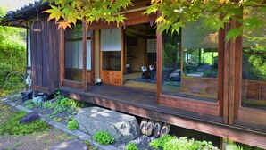 A traditional Japanese-style building with a wooden exterior, large sliding glass doors, and a stone pathway leading to the entrance. - Kotorian (Asuka)