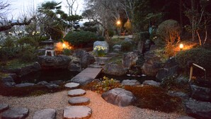 A traditional Japanese garden with a stone bridge, stepping stones, and a small pagoda. - Kotorian (Asuka)