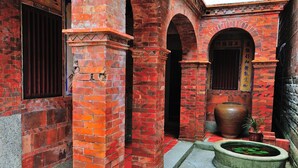 A courtyard with red brick walls, a large vase, and a small pond. - Feng Mao Lin Zh (Jincheng)