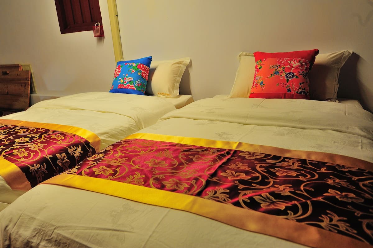A double bed with two pillows, one with a floral pattern and the other plain.
