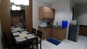 Una cucina funzionale con mobili in legno, un tavolo da pranzo con sedie, un tappeto blu e un frigorifero.